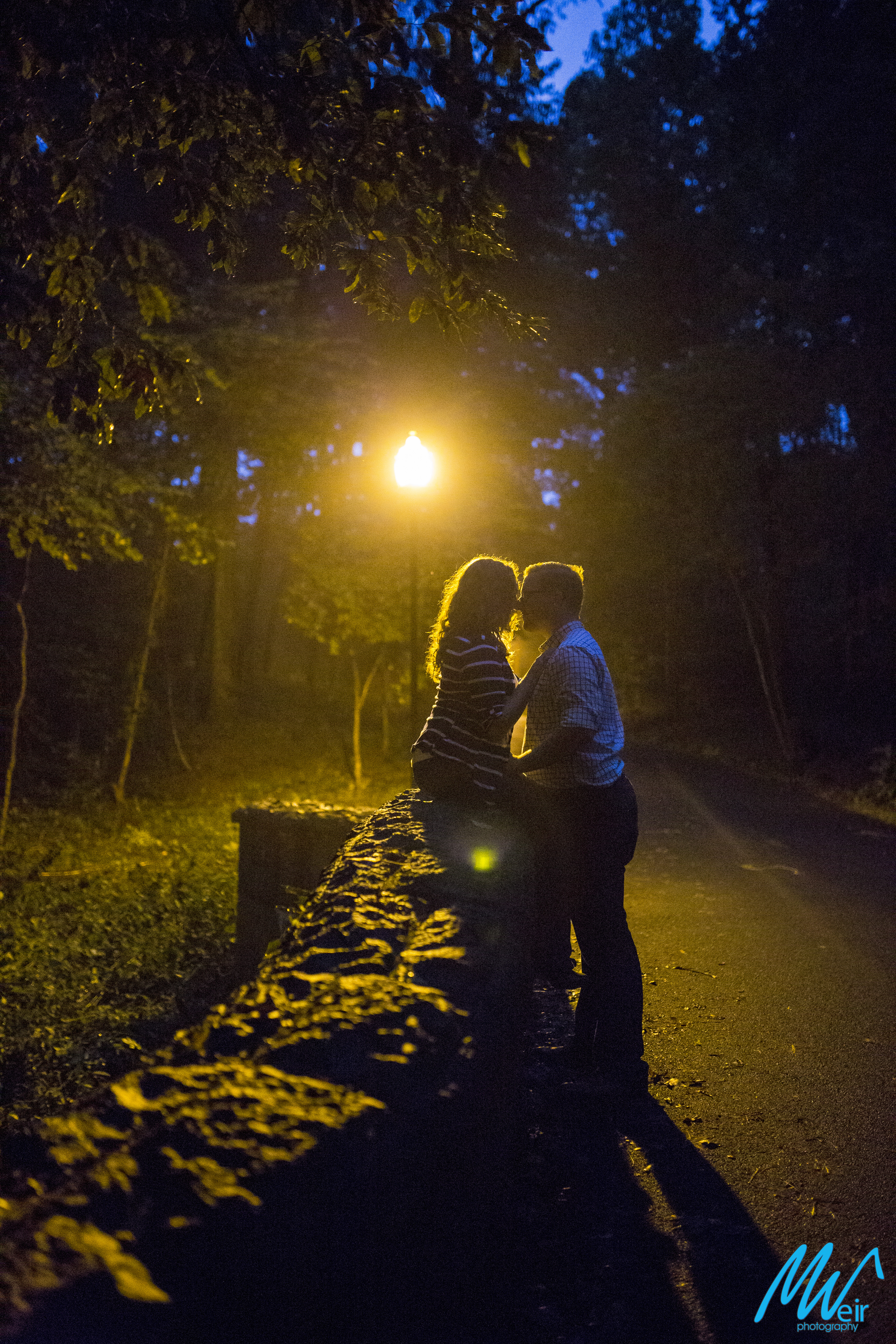 couple sit on a stone wall together at night
