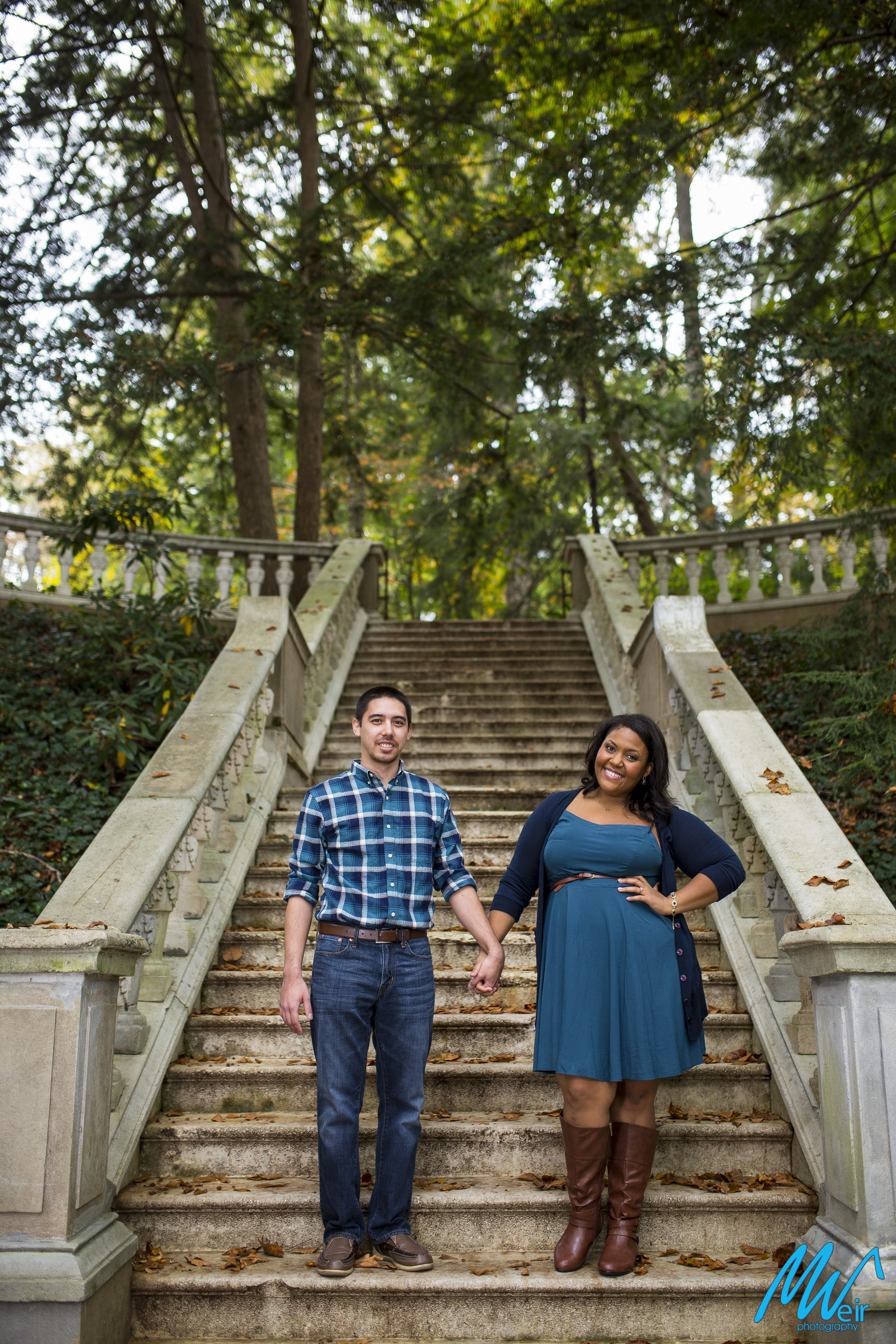couple looking at camera standing in front of grand stone staircase