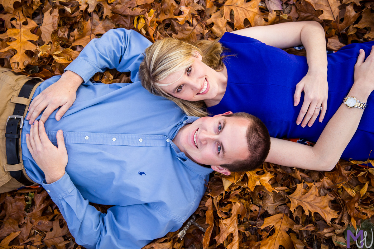 engagement photos laying in the fall leaves